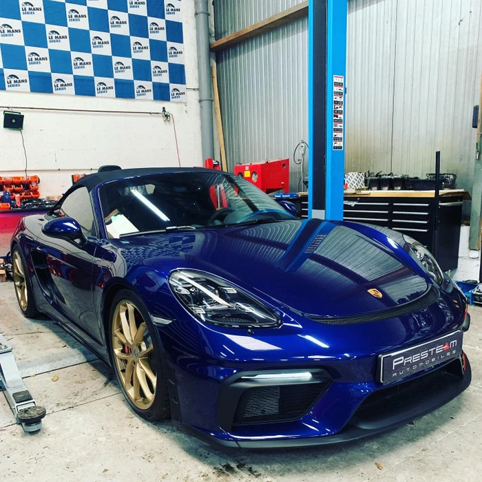 Atelier mécanique intérieur, Porsche 718 Boxster cabriolet bleu nuit métallisé, jantes alliage dorées, soft-top noir replié