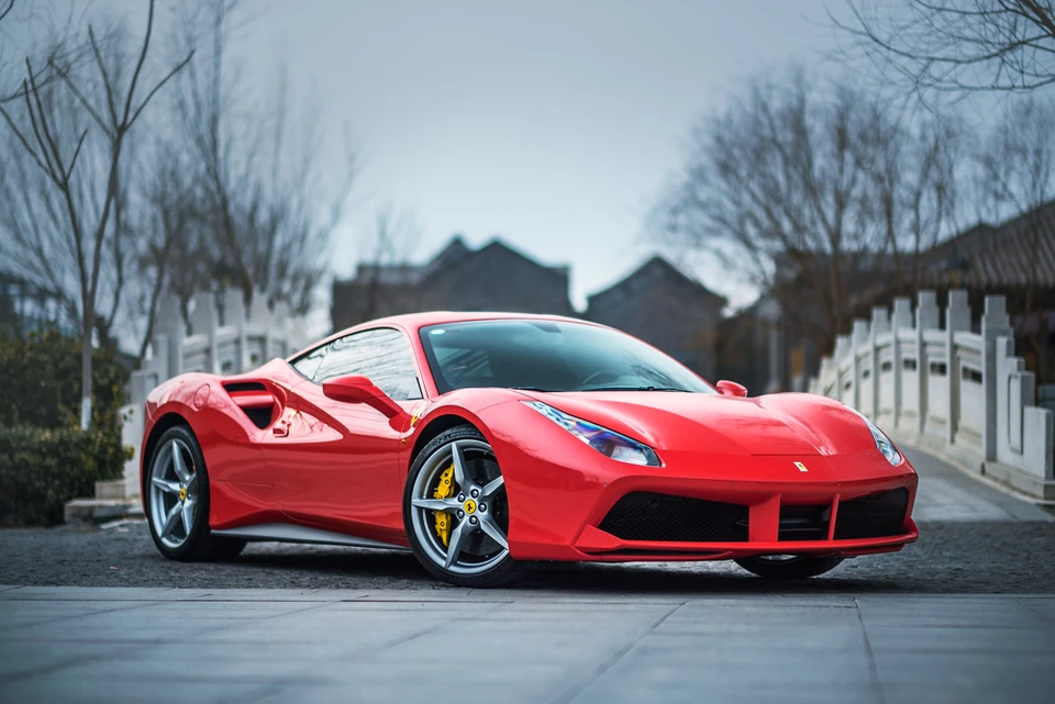 Scène extérieure urbaine avec Ferrari 488 GTB rouge stationnée sur chaussée pavée près d'un pont à balustrade blanche