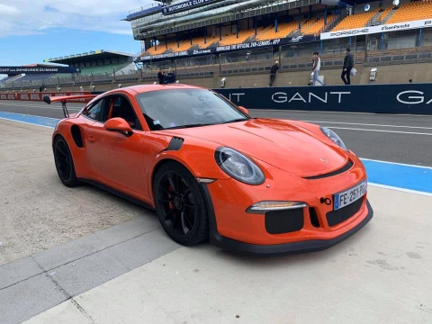 Porsche 911 GT3 RS orange vif stationnée dans la voie des stands du Circuit des 24 Heures du Mans