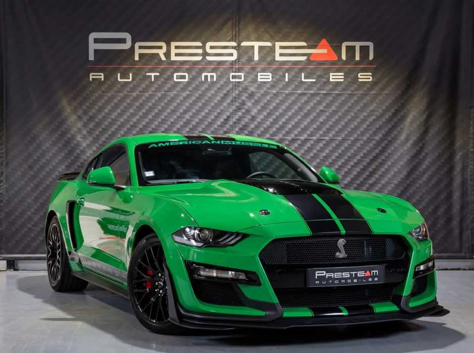 Ford Mustang Shelby GT500, carrosserie vert vif avec bandes racing noires sur le capot, emblème cobra sur la calandre noire, jantes noires, étriers de frein rouges