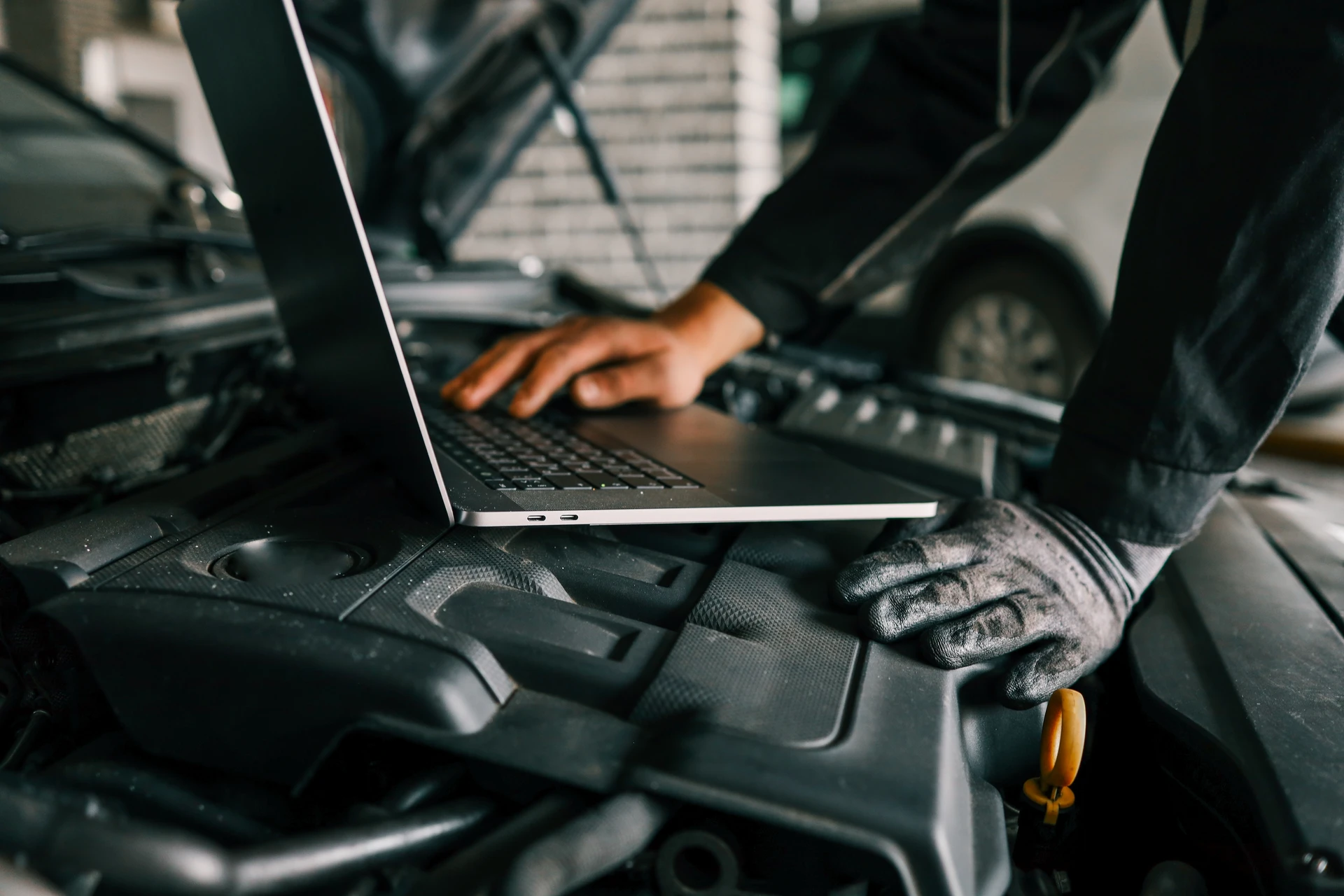 Atelier de réparation automobile moderne avec mécanicienne professionnelle en combinaison bleue et lunettes de sécurité consultant une tablette numérique